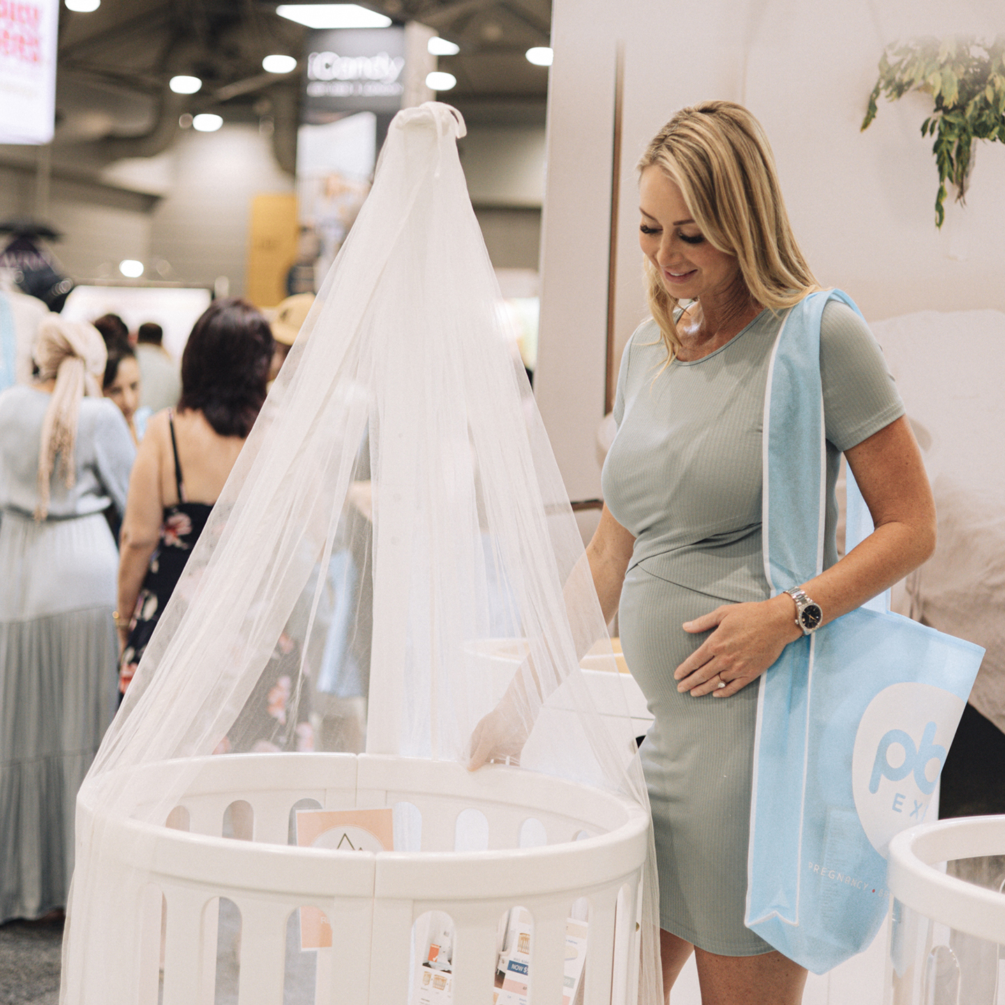 Pregnant woman is touching a baby bassinet at baby expo